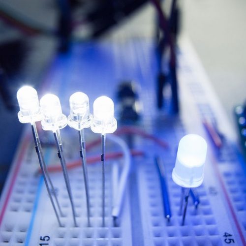 Light-emitting diodes on breadboard electrical panel. Close-up of blue led, shining on engineer workplace. Electrician-inventor laboratory